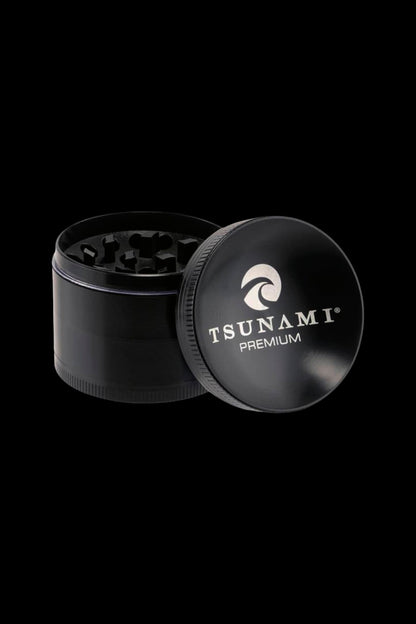 Black metal cannabis grinder with open lid displaying “Tsunami Premium” logo.