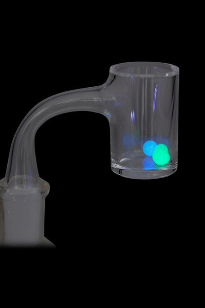 Close-up of a glass banger holding two glowing blue and green beads, "The Stash Shack Glow in the Dark Quartz Terp Pearls - 2pc" visible at the cup.