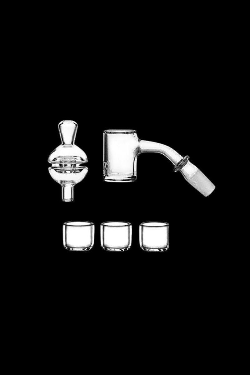 Clear glass dab rig components including a carb cap, banger, and three small silicone containers, isolated on a black background.