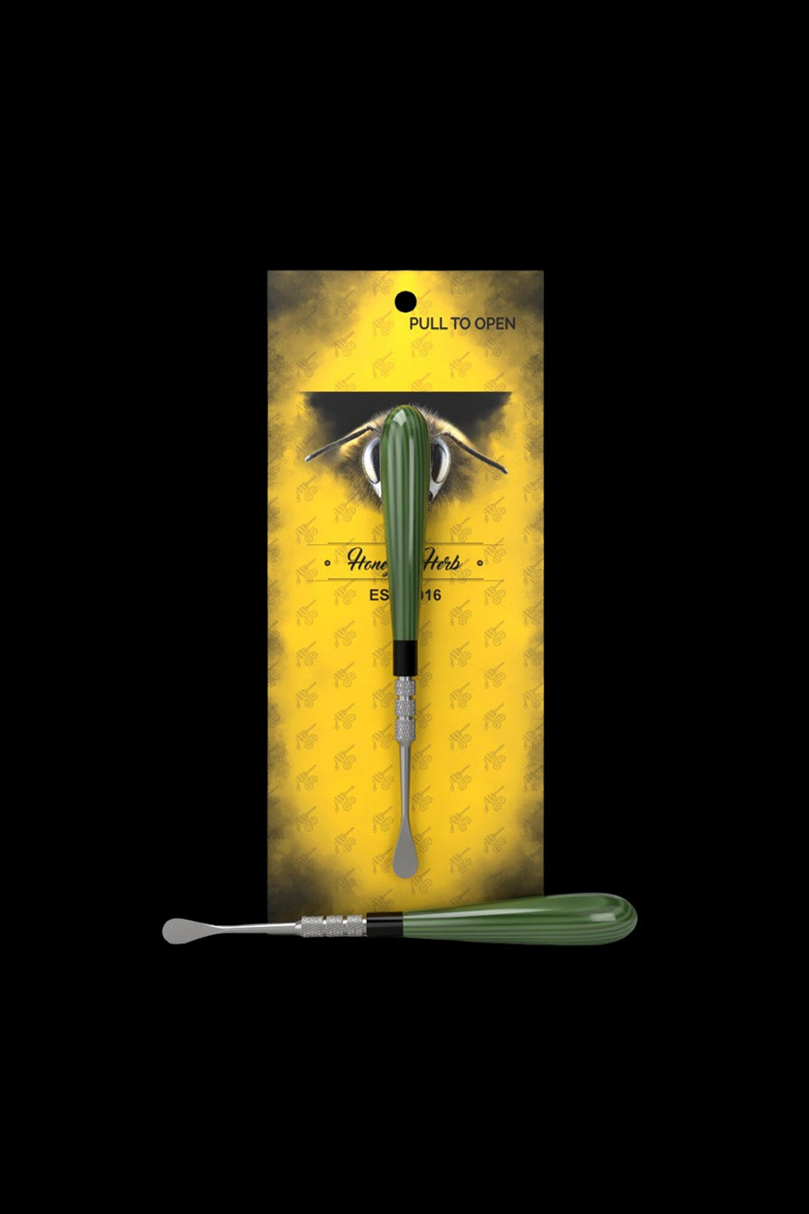 Top-down view of the green Honeybee Herb Classic Dab Tool centered on yellow branded packaging with a bee motif.