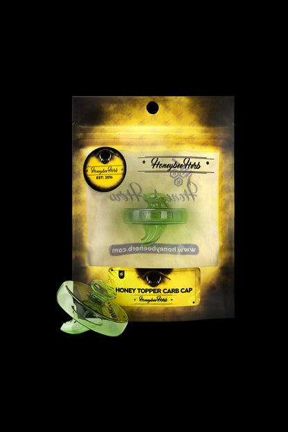 Top-down view of the green Honeybee Herb Honey Topper Carb Cap resting beside its yellow branded packaging.