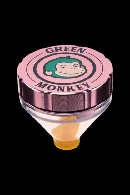 Close-up top-down view of the Silver Green Monkey Patas Grinder lid showing a pink cap with the smiling green-haired monkey logo against a black background.