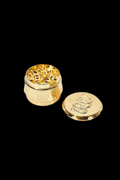 Gold cannabis grinder with lid detached, displaying internal grinding teeth.