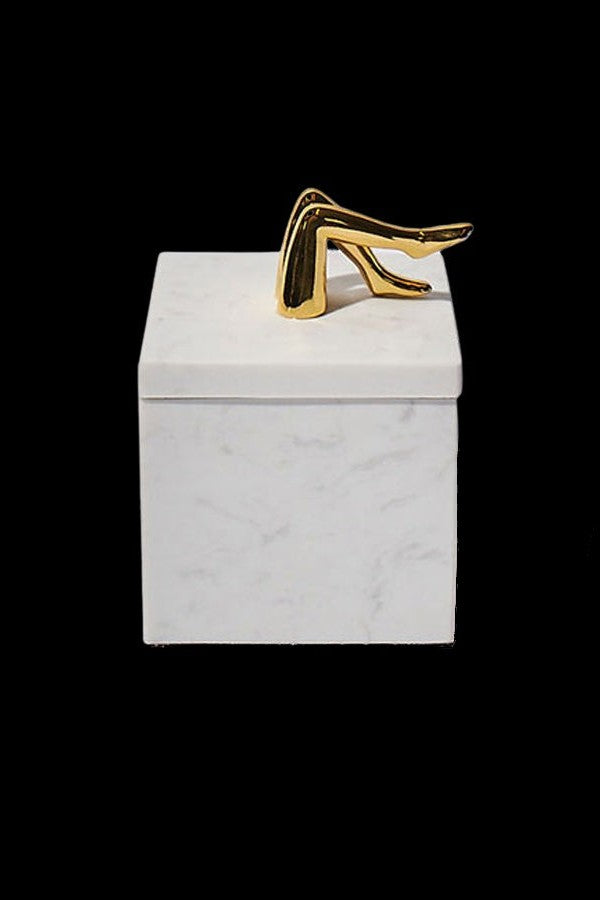 Gold cannabis oil applicator tip resting on a white box.