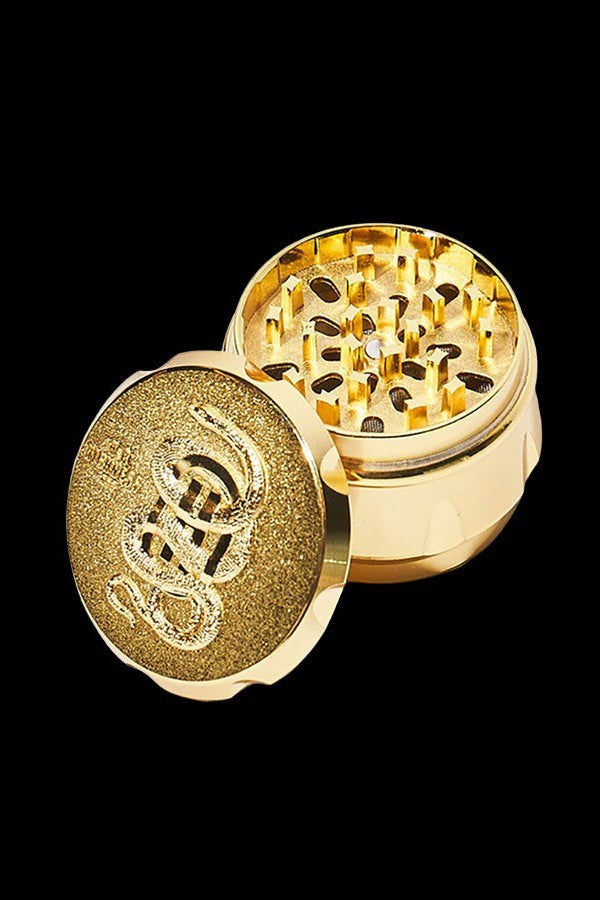 Gold cannabis grinder with lid removed, revealing metal teeth and chamber.