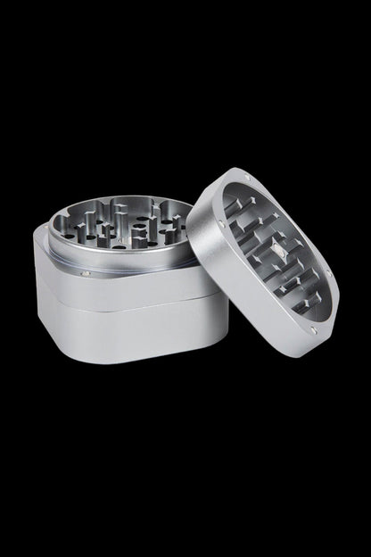 Silver cannabis grinder, open to reveal the multi-tiered grinding mechanism.