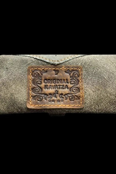 Close-up of a textured, olive-green cannabis accessories case with a leather patch reading "Original Kavatza".