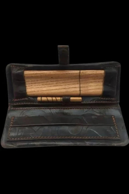 Open dark leather cannabis case with wooden rolling papers inside.