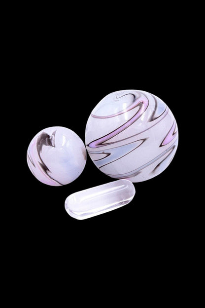 Glass marbles with lavender and white swirls, displayed against a black background.