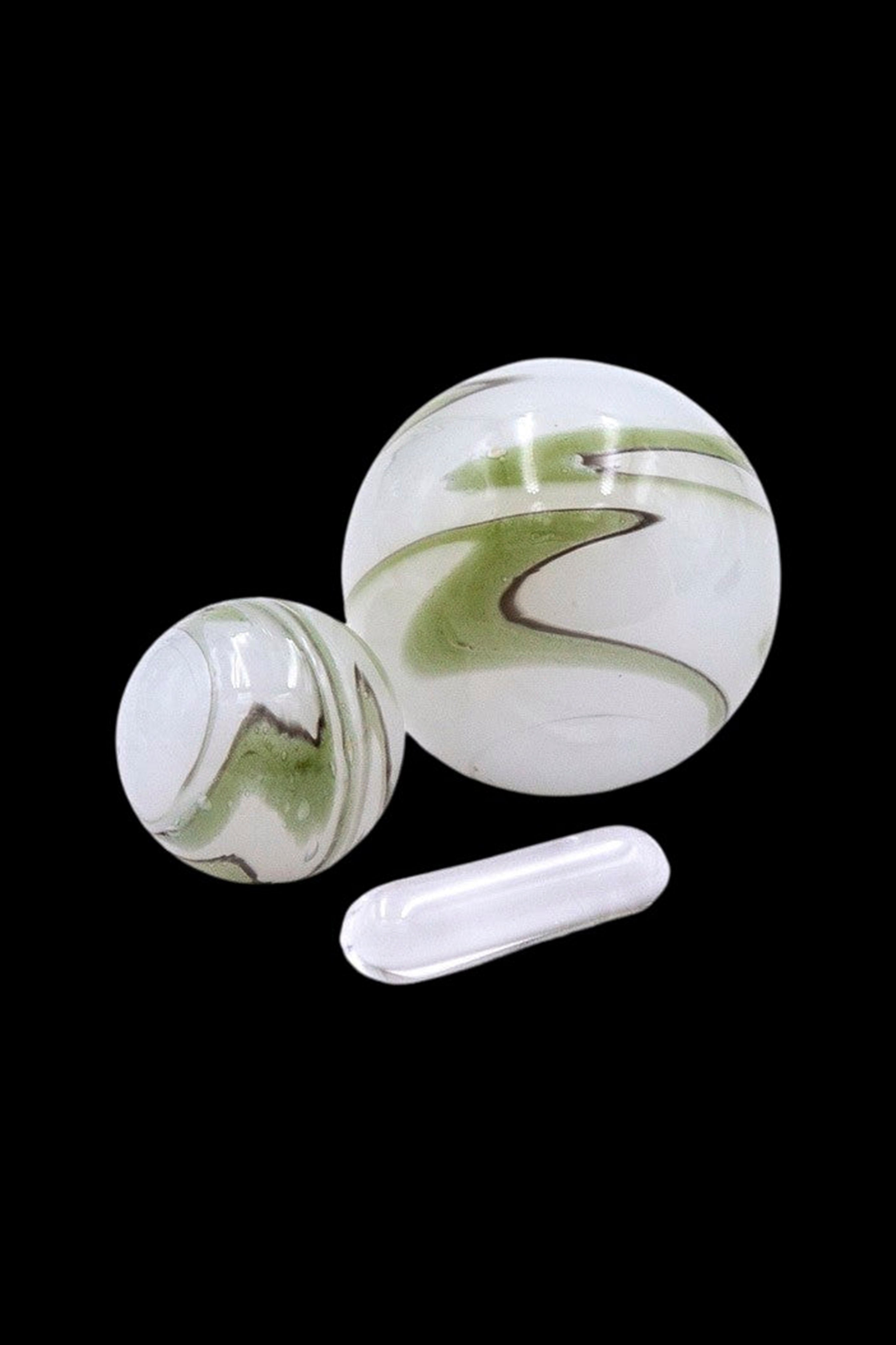 Green and white glass marbles and a small glass pipe on a black background.