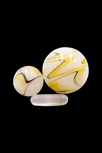 Hand-blown glass marbles and dab tool on black background.