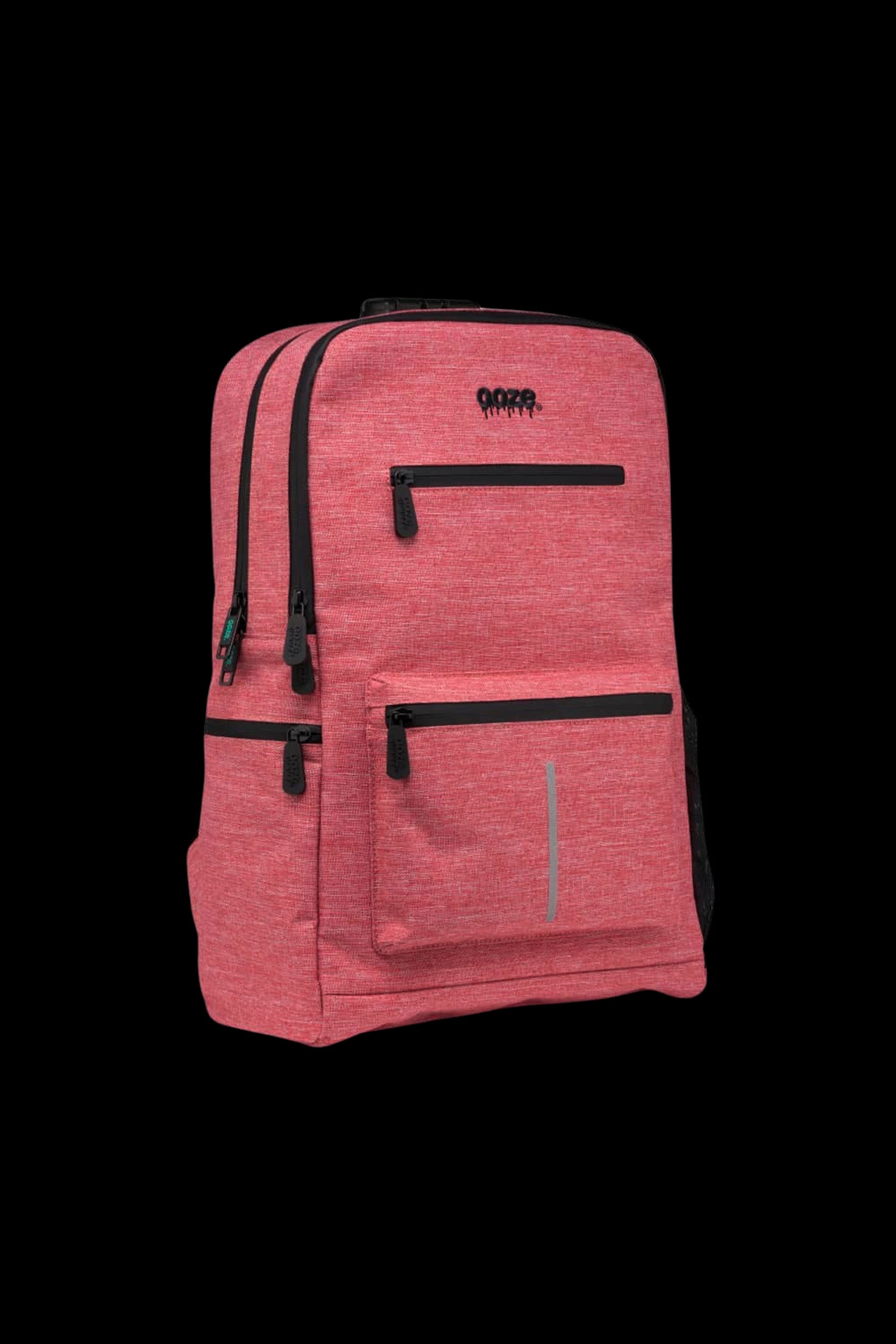 Three-quarter front view of the Smoke Gray Ooze Traveler Smell Proof Backpack showing textured fabric, black zippers, multiple front pockets, and reflective strip.