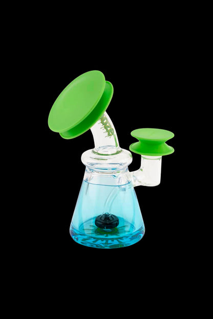 Close-up of a glass rig topped with two bright green Ooze Resolution Caps Cleaning Caps placed on the mouthpiece and side port against a black background