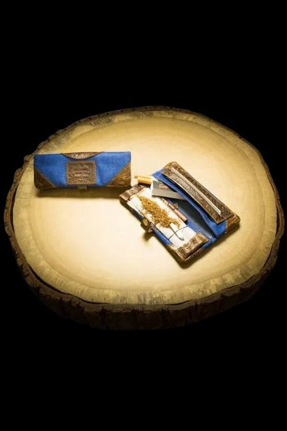 Ornate cannabis rolling kit with a joint and accessories displayed on a wood slice.
