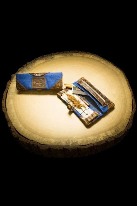 Ornate cannabis rolling kit with a joint and accessories displayed on a wood slice.