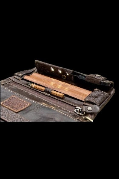 Brown leather cannabis case open, displaying a rolled joint and accessories.