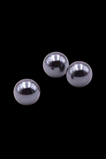 Silver glass marbles against a black background, likely for use in a water pipe or dab rig.