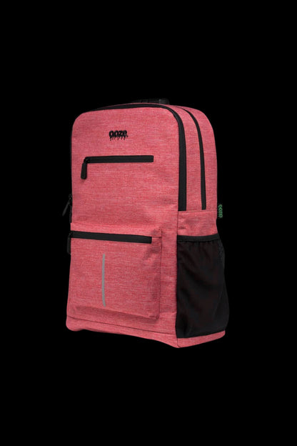 Three-quarter view of a purple-hued Ooze Traveler Smell Proof Backpack against a black background, showing front pockets, black trim, and mesh side pocket.