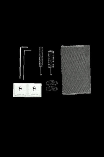 Cannabis accessory cleaning kit with brushes, pipe cleaners, and wipes on a dark background.