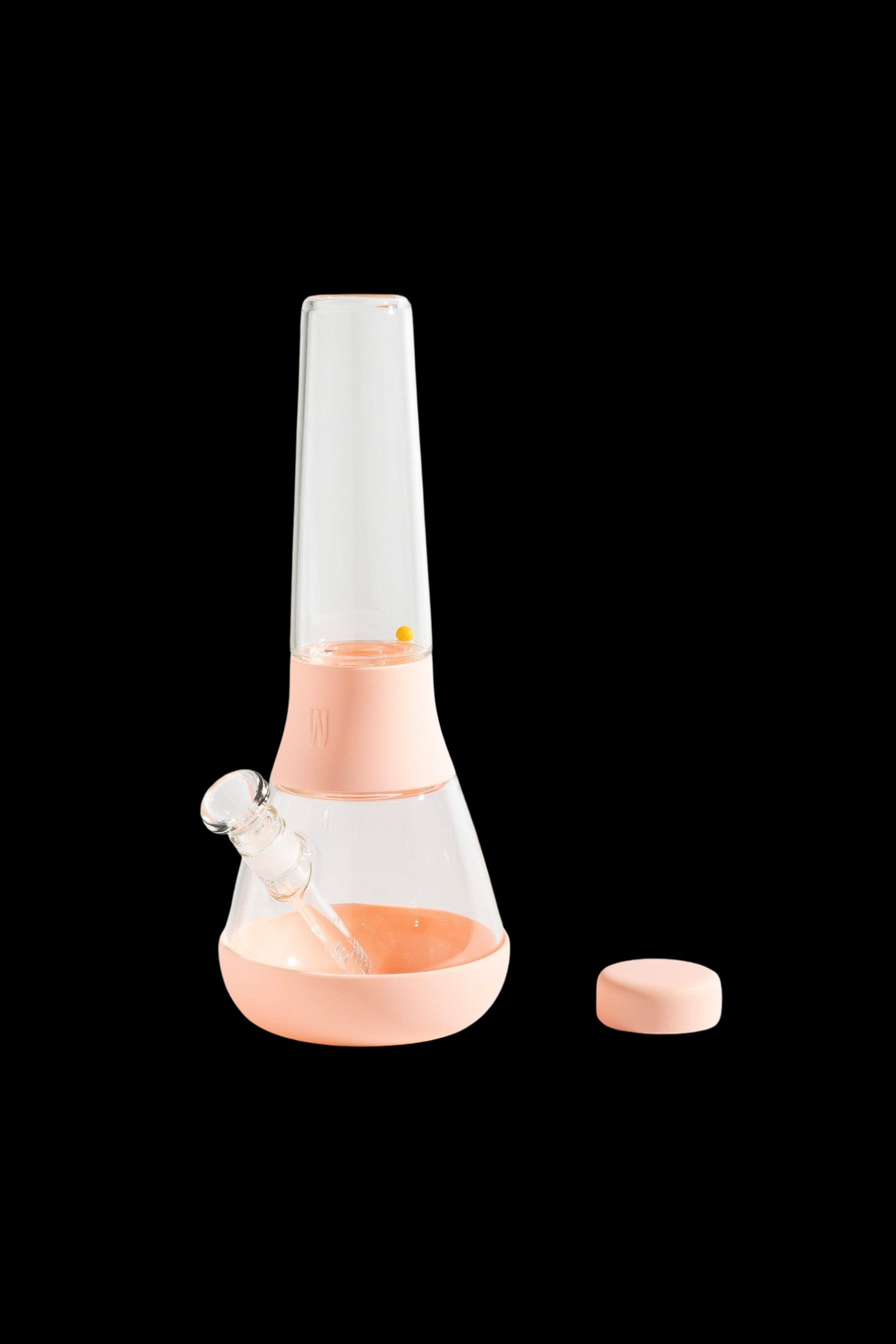 Peach-colored glass bong with a removable downstem and cap, isolated on a black background.