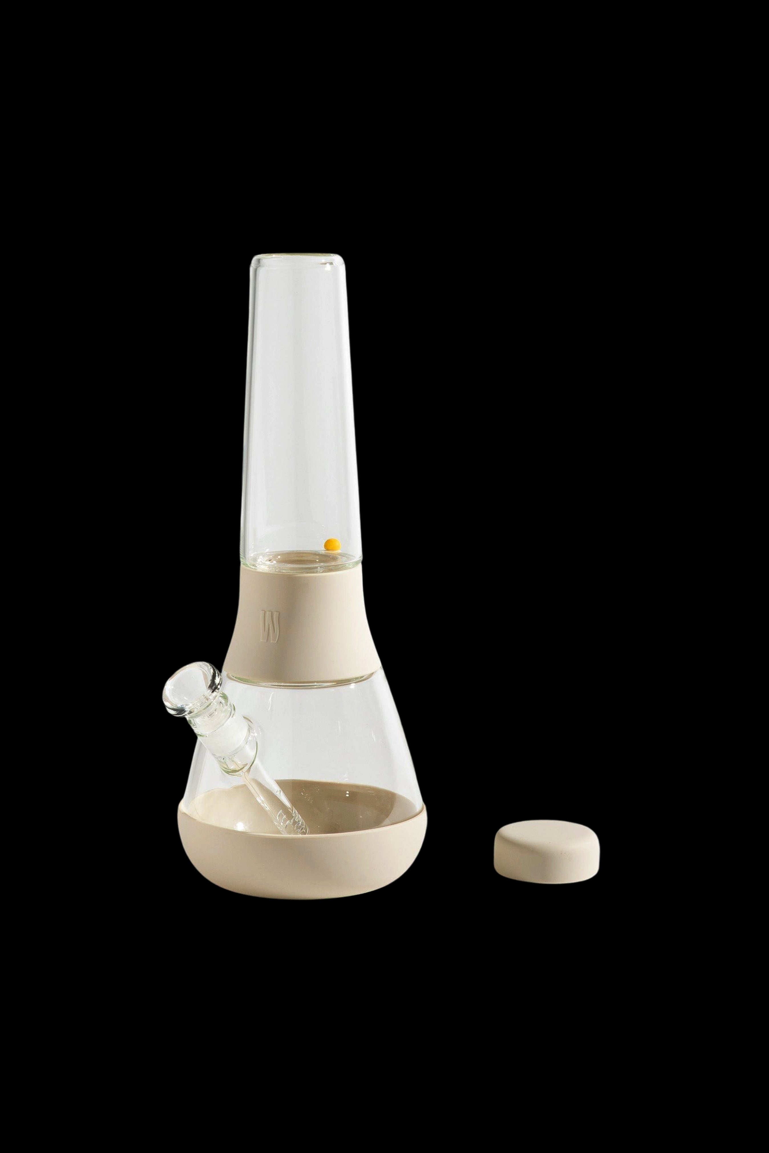 Beige and clear glass bubbler water pipe with a removable downstem and silicone stopper, isolated on a black background.