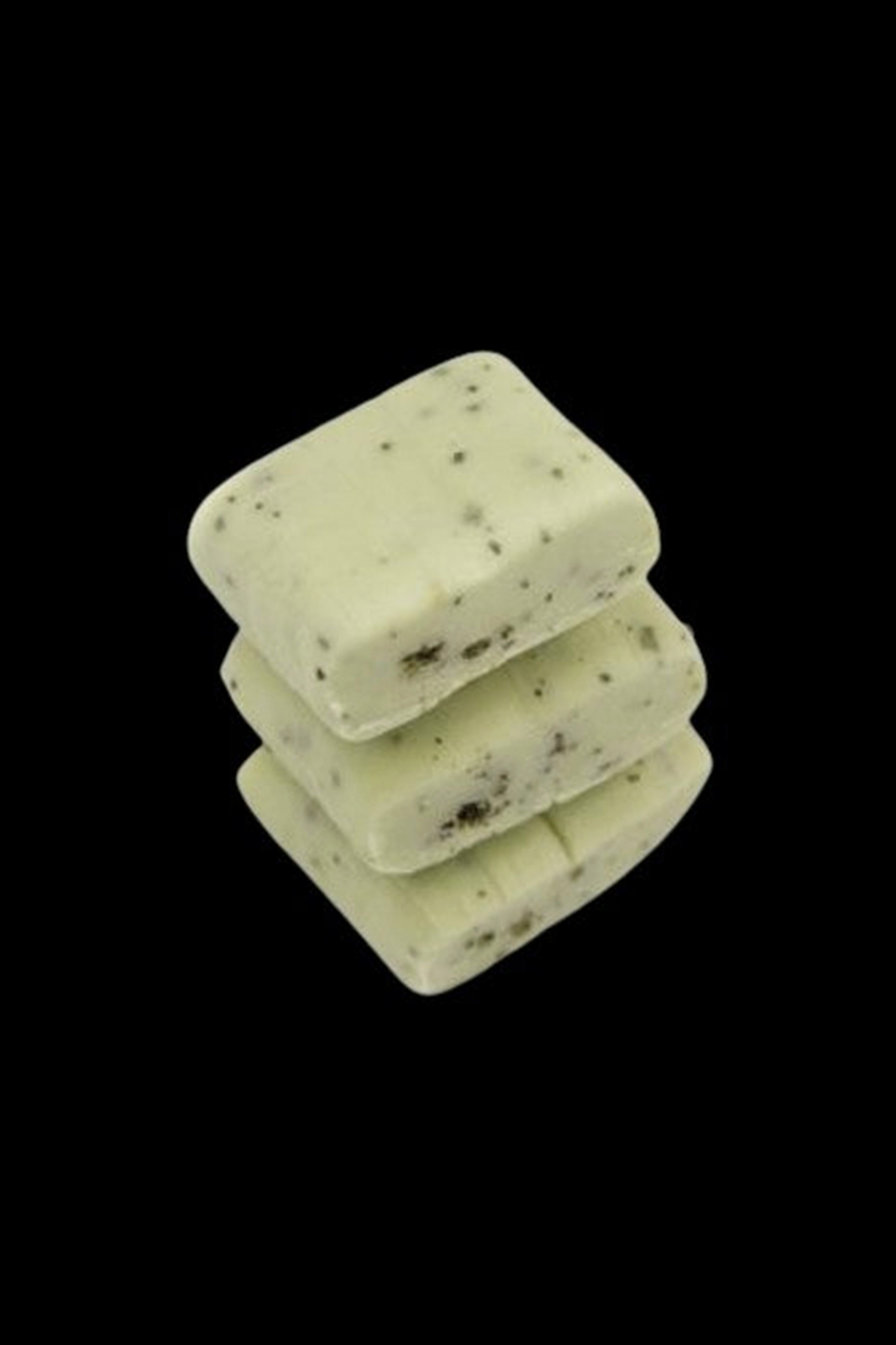 Stack of green cannabis-infused wax melts with visible plant flecks.