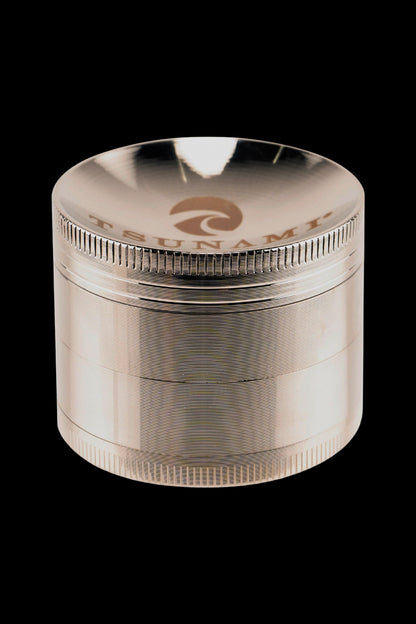 Clear four-piece cannabis grinder with metallic threading and a branded top.