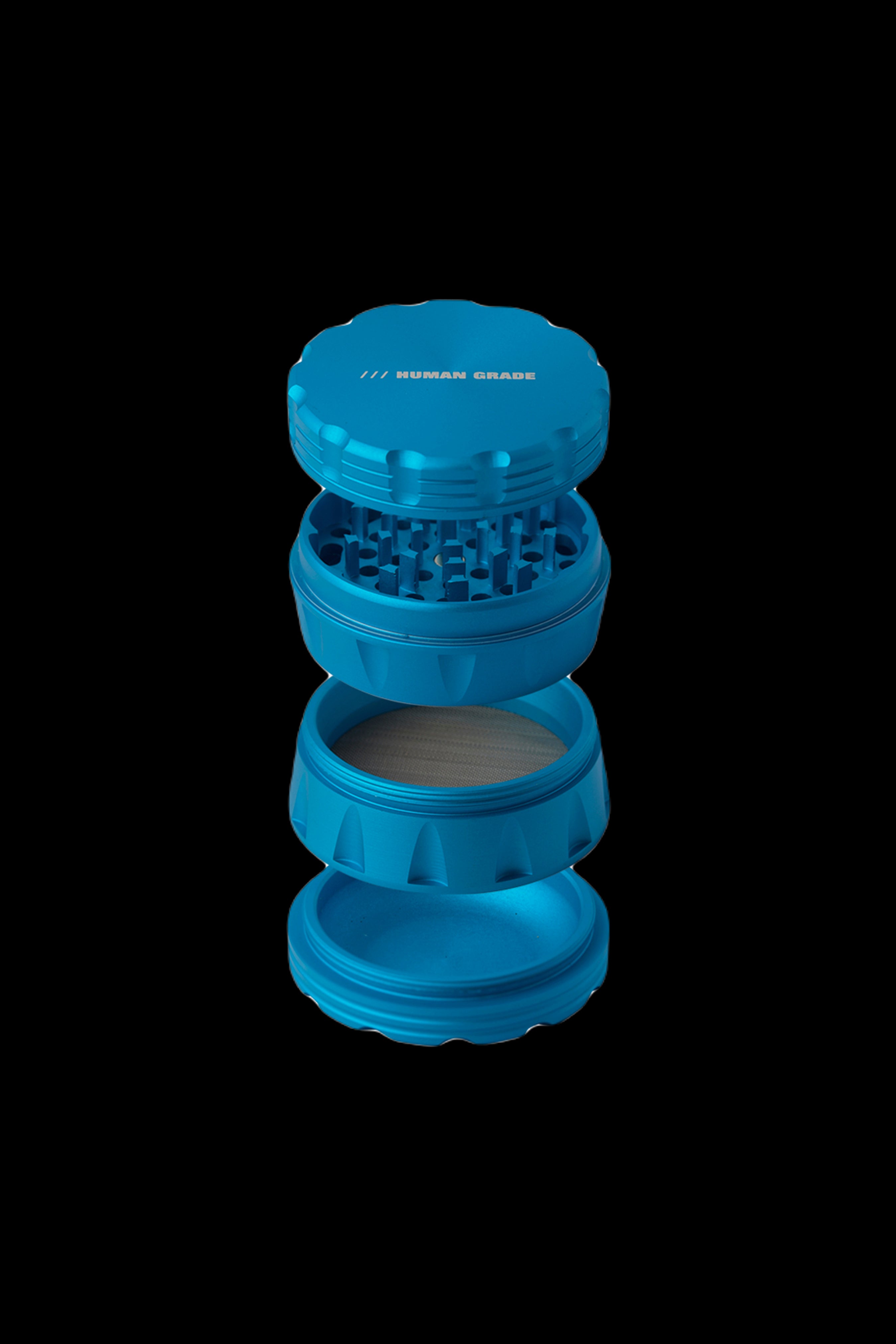 Blue four-piece cannabis grinder with "/// HUMAN GRADE" text on the lid.