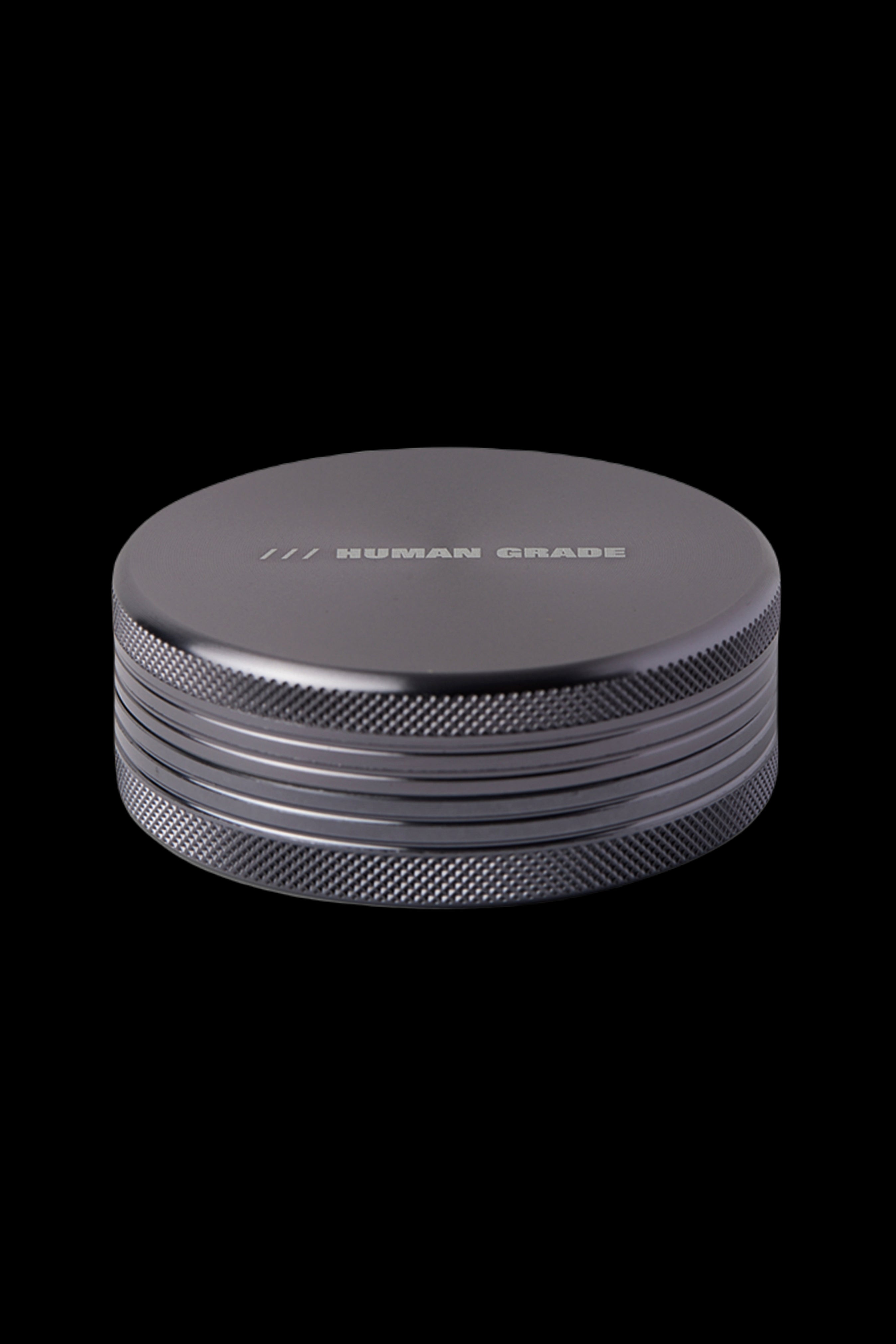 Black metal cannabis grinder with "HUMAN GRADE" engraved on top.