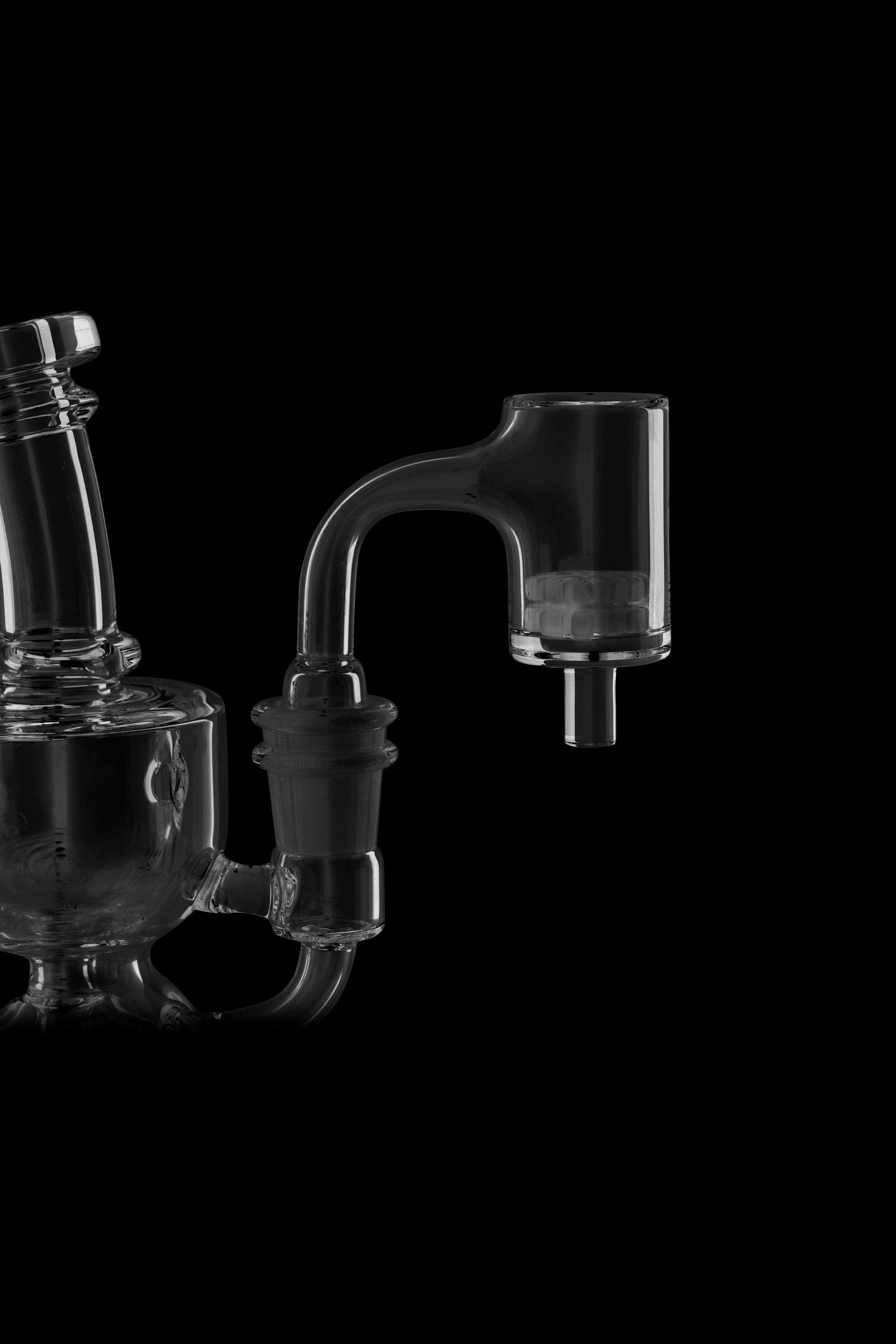 Glass dab rig and quartz banger on black background.