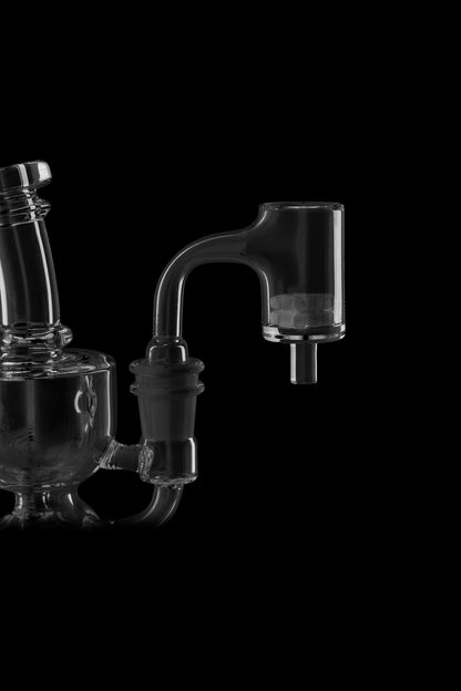 Glass dab rig and quartz banger on black background.