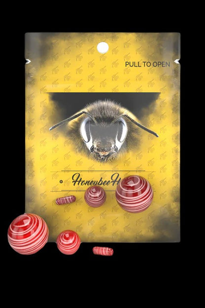 Packaging for “Honeybee” cannabis concentrates featuring a bee illustration and red hash pellets.