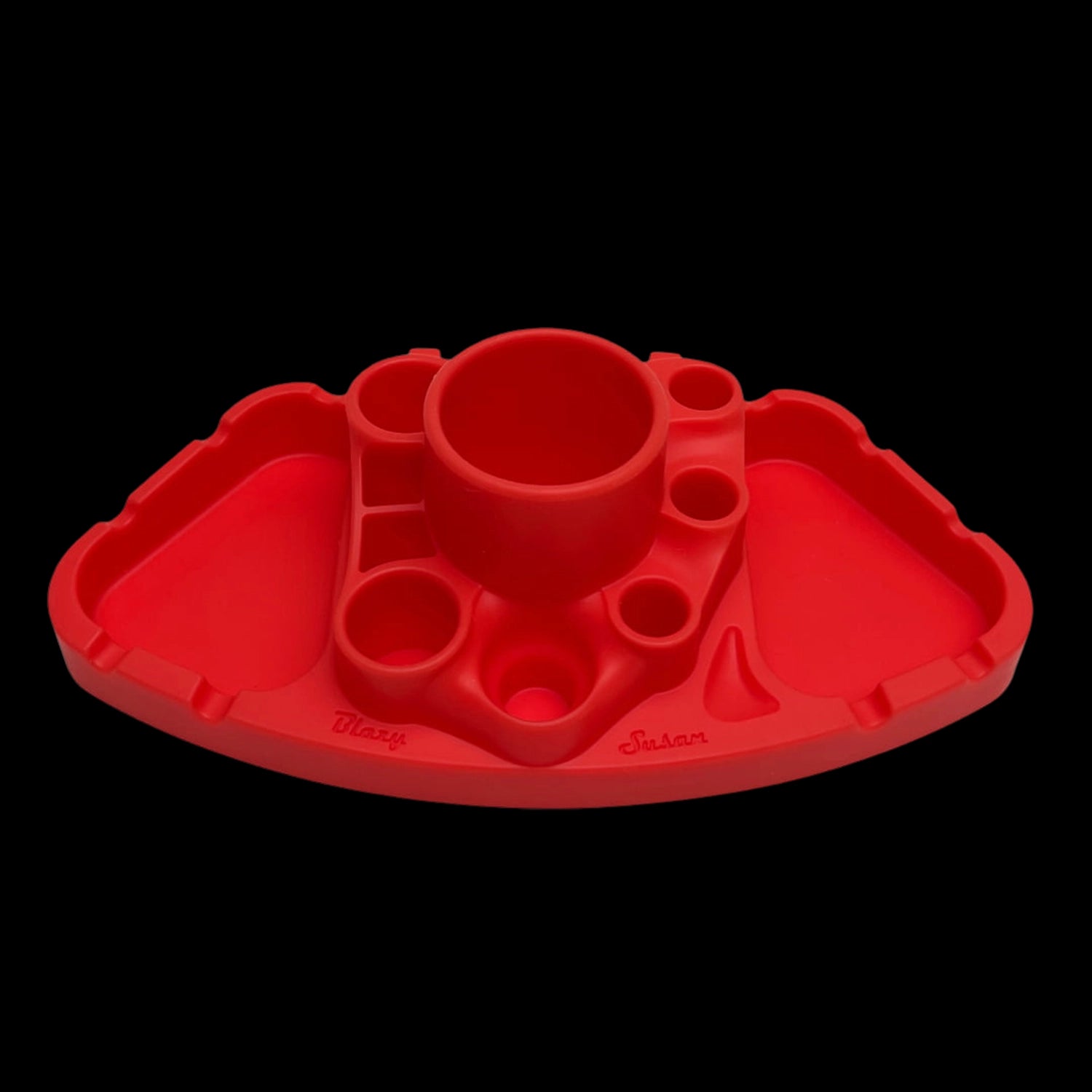Low-angle front view of the orange Blazy Susan Deluxe Dab Station showing its central cup, multiple circular wells, and triangular side trays against a black background.