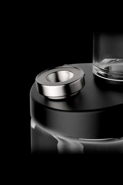 Close-up of a cannabis vape pen's metallic button and glass cartridge against a black background.