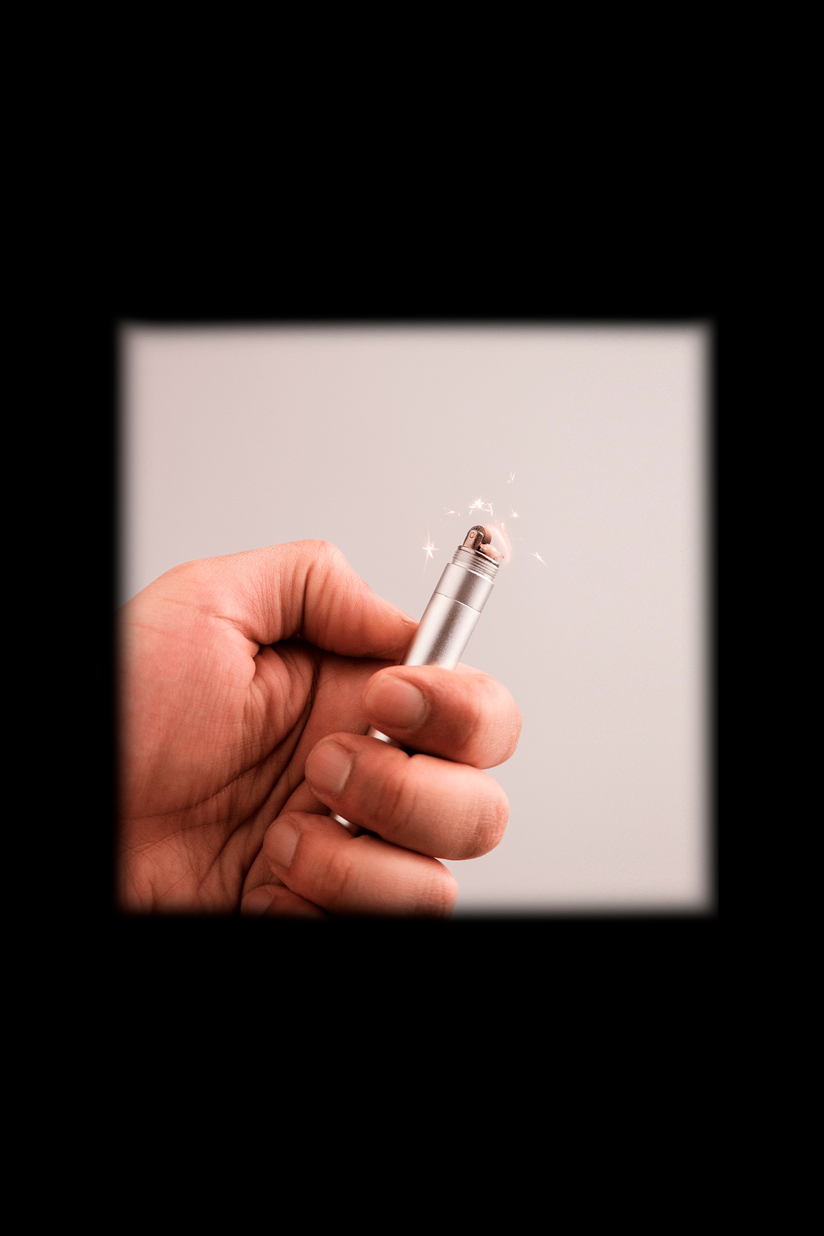 Hand holding a lit butane lighter, sparks visible.