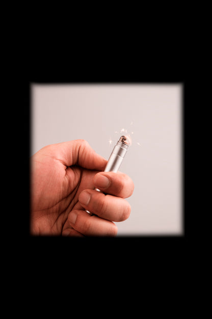 Hand holding a lit butane lighter, sparks visible.