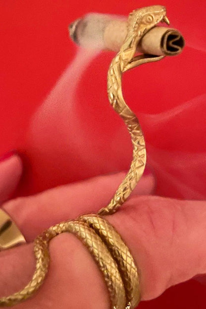Golden snake-shaped smoking accessory holding a rolled cannabis joint.