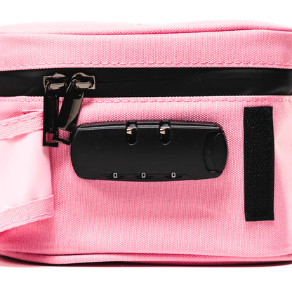 Close-up side view of a pink Blazy Susan Stash Bag showing black zipper pulls and an attached three-digit combination lock against textured fabric.