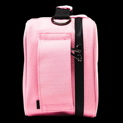 Close-up side view of a pink Blazy Susan Stash Bag showing a vertical black zipper, metal zipper pulls and a stitched fabric strap with a metal D-ring.