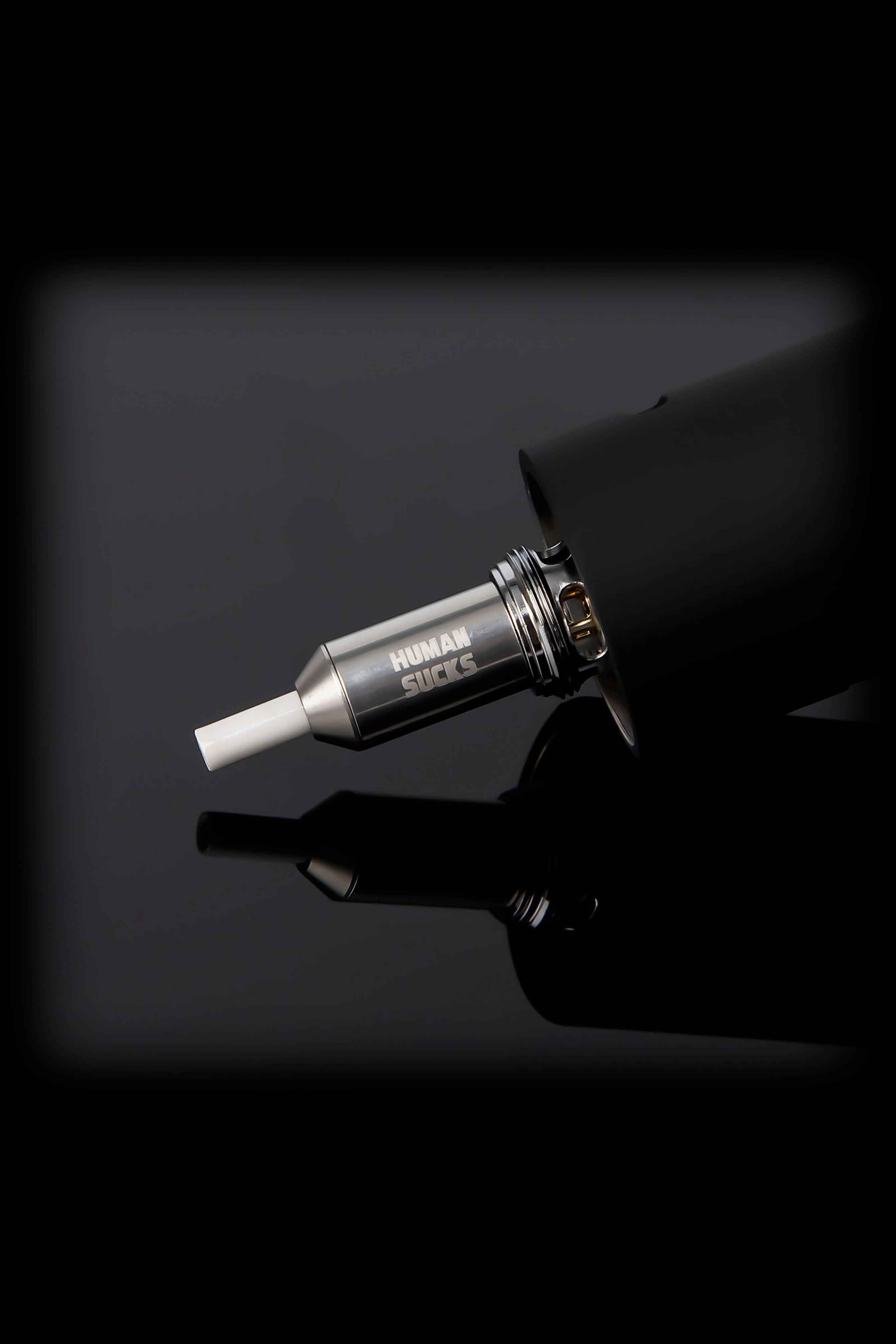 A sleek, black cannabis oil vaporizer pen with a metallic mouthpiece displaying the text "HUMAN SUCKS."