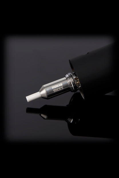 A sleek, black cannabis oil vaporizer pen with a metallic mouthpiece displaying the text "HUMAN SUCKS."
