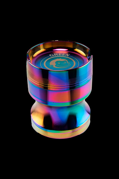 Close-up top-down view of the Green Monkey Chacma Grinder with Ashtray showing its iridescent rainbow finish and recessed ashtray rim against a black background