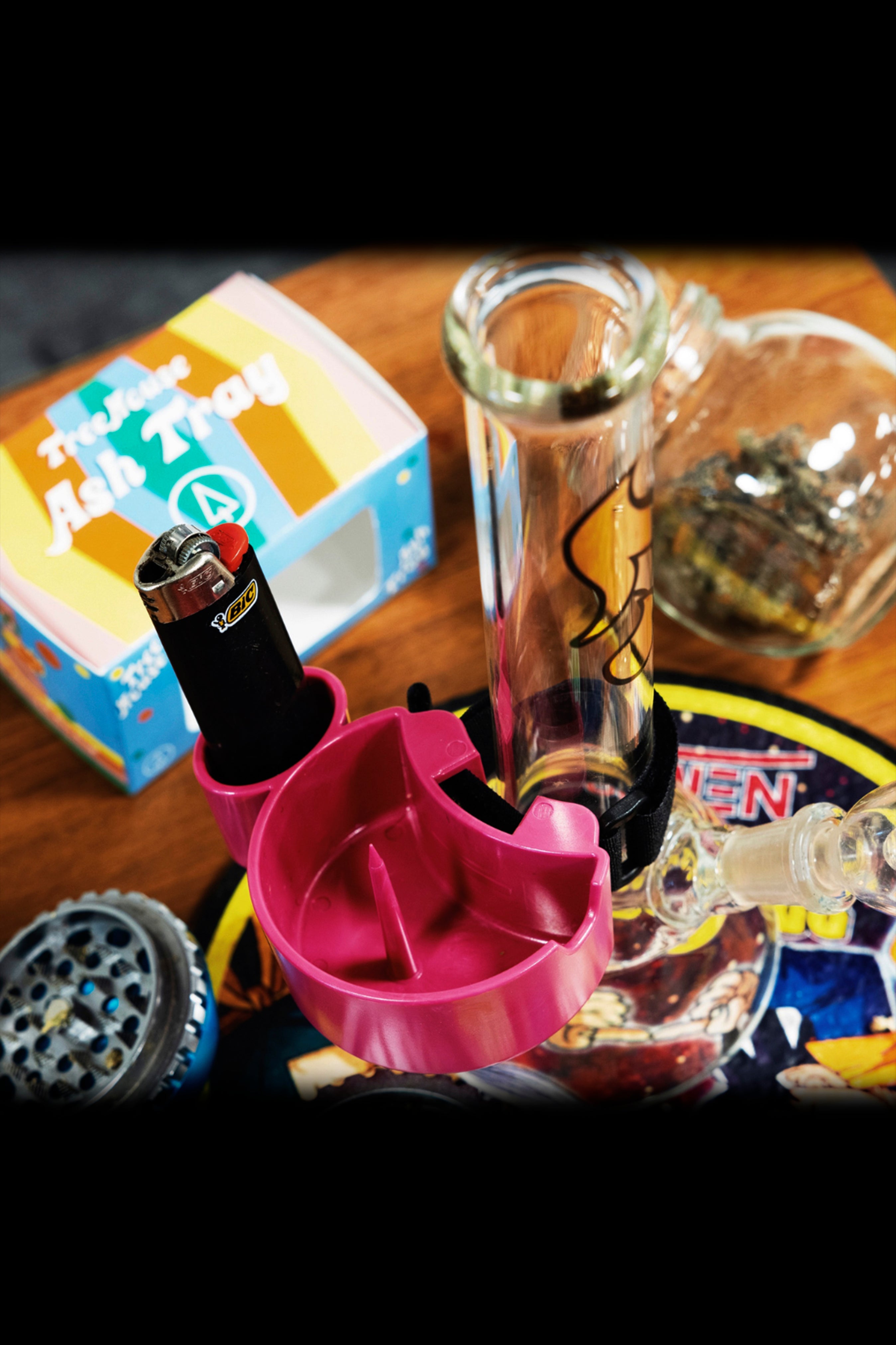 Close-up of cannabis smoking accessories including a glass pipe, grinder, lighter, and ashtray."