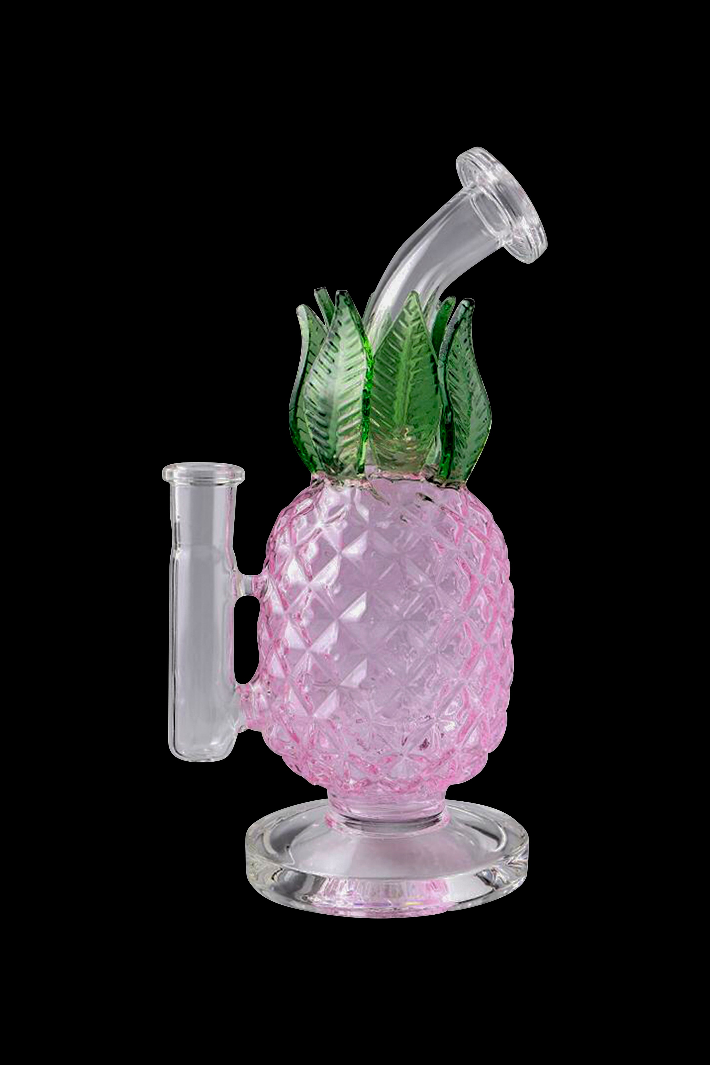 Pink glass water pipe shaped like a pineapple with green leaf accents, studio shot on black background.