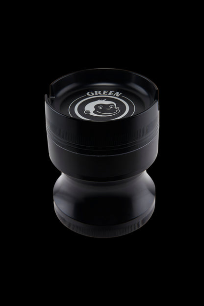 Top-down close-up of the Green Monkey Chacma Grinder with Ashtray showing the black lid, white monkey logo and stepped cylindrical body.