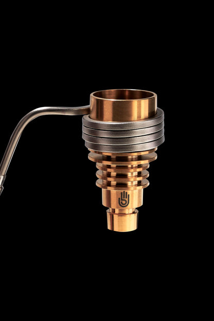 Bronze cannabis concentrate vaporizer coil with a glass carb cap and metal tubing, isolated on a black background.