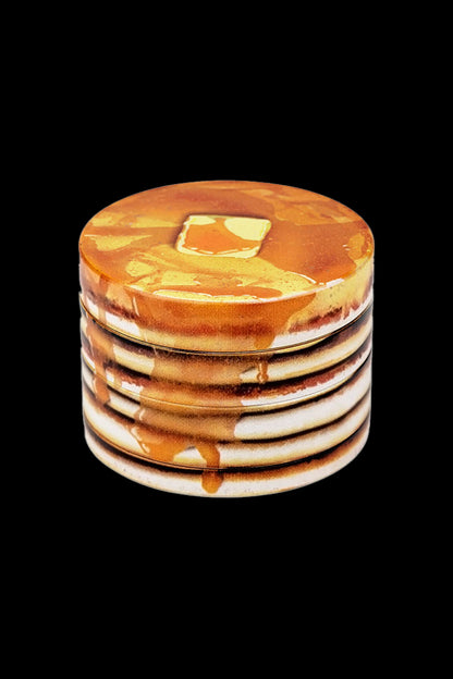 Pancake-shaped cannabis grinder with dripping honey design on a black background.