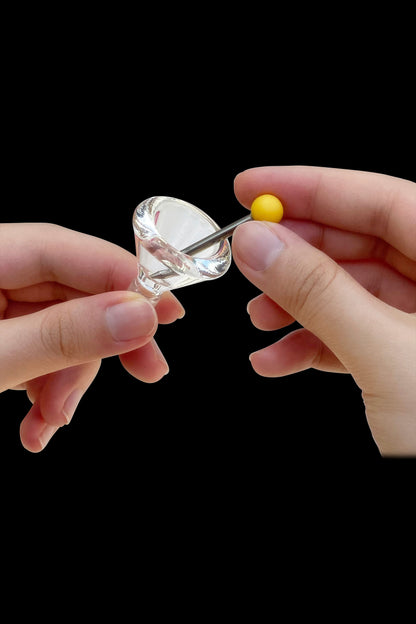Hands applying cannabis concentrate to a glass dab rig.