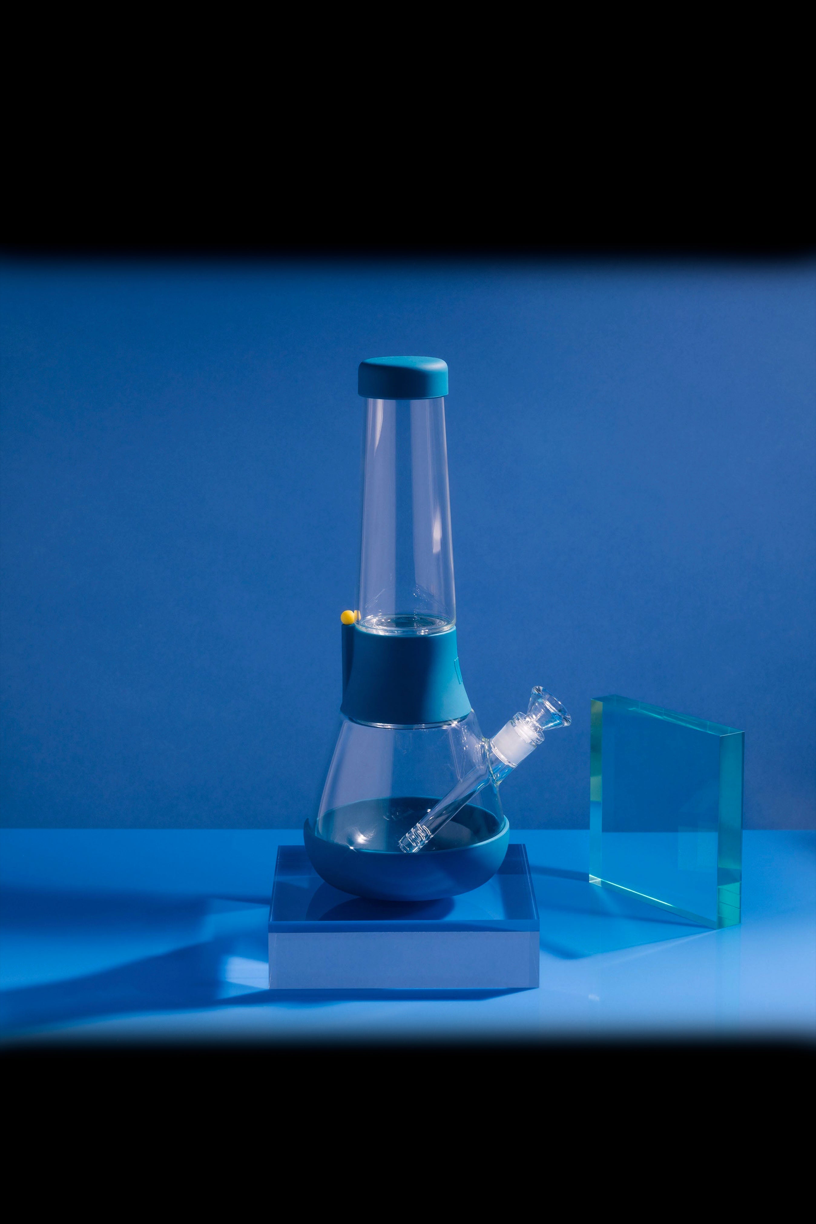 Blue glass bubbler water pipe with a silicone base, studio shot.