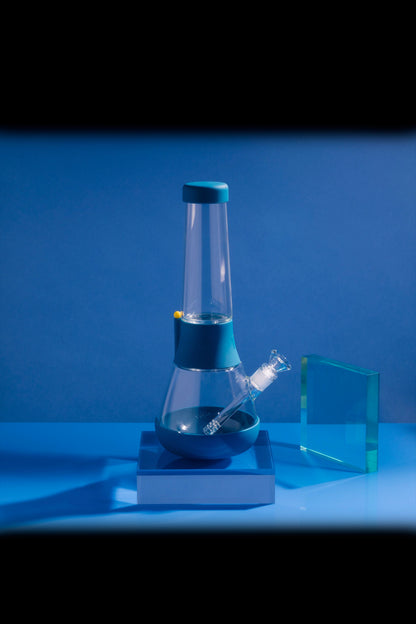 Blue glass bubbler water pipe with a silicone base, studio shot.